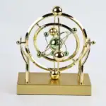 Modèle atomique décoratif en métal doré avec sphères vertes et or, représentant un atome stylisé.