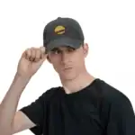 Jeune homme portant une casquette noire avec un logo de planète, regardant vers la droite, fond blanc.