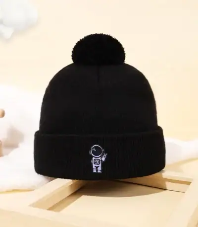 Bonnet noir en laine avec pompon et logo d'un astronaute, idéal pour les amateurs de science et d'astronomie, parfait pour l'hiver ou comme accessoire de décoration scientifique.