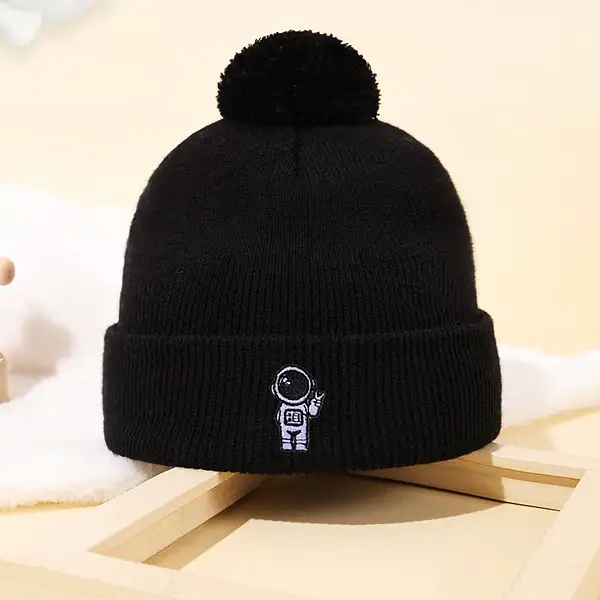 Bonnet noir en laine avec pompon et logo d'un astronaute, idéal pour les amateurs de science et d'astronomie, parfait pour l'hiver ou comme accessoire de décoration scientifique.