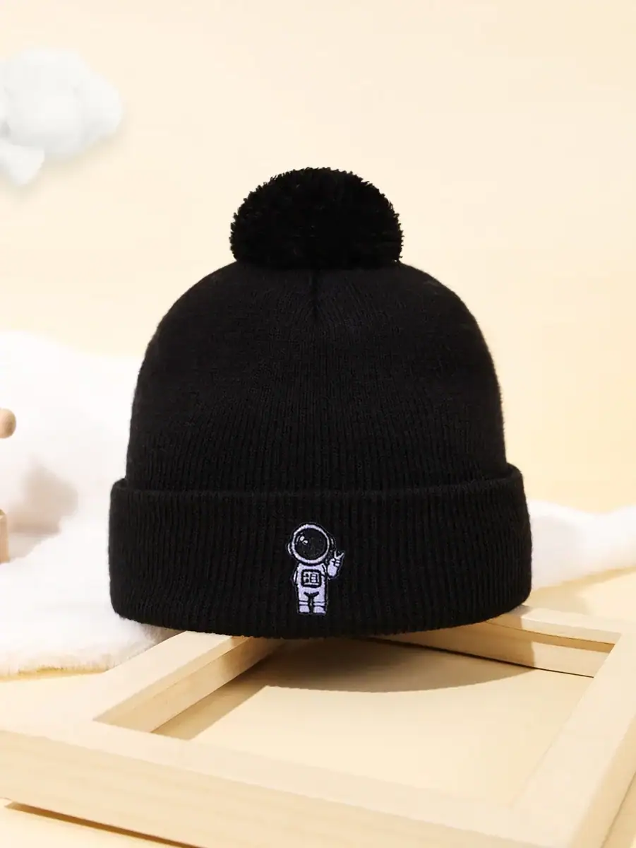 Bonnet noir en laine avec pompon et logo d'un astronaute, idéal pour les amateurs de science et d'astronomie, parfait pour l'hiver ou comme accessoire de décoration scientifique.