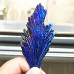 Stibine cristallisée aux reflets irisés, exposée dans une main.