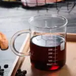 Tasse de laboratoire en verre contenant un liquide foncé, graduée pour mesurer précisément le volume, idéale pour expériences scientifiques ou décoration thématique.