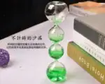 Pied à verre en verre avec deux boules transparentes et liquide vert, parfait pour la décoration scientifique ou comme objet de collection.