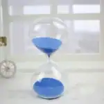 Sablier de laboratoire avec sable bleu, symbole de la mesure du temps, idéal pour la décoration scientifique ou éducative.