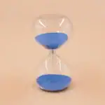 Sablier en verre transparent rempli de sable bleu, symbole du temps qui passe, idéal pour la décoration scientifique ou éducative.