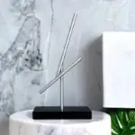 Objet scientifique en décoration minimaliste avec tubes en métal et base noire.