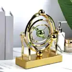 Horloge décorative scientifique en métal doré avec sphères vertes, design élégant et moderne, idéale pour la décoration de bureau ou d'étagère.