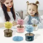 Petit arbre en cristal coloré dans un pot, idéal pour décoration ou activité ludique pour enfants, avec une mère et une fille jouant ensemble.