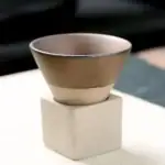 Petit pot en céramique beige posé sur un socle en béton blanc, idéal pour la décoration scientifique ou de bureau.