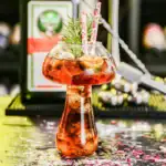 Verre de cocktail original en forme de ballon de laboratoire, décoré avec des branches de sapin, parfait pour une décoration de fête ou un événement scientifique.