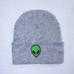 Bonnet gris en laine avec patch d'alien vert brodé, idéal pour un style décontracté et original. Parfait pour les amateurs de science-fiction et de design unique.