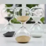 Sablier en verre avec sable blanc et noir, symbole du temps qui passe, décoratif et scientifique, idéal pour une décoration de bureau ou d'étagère.