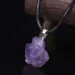 Pendentif en améthyste brute suspendu à un cordon noir, mettant en valeur la pierre semi-précieuse violette.
