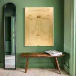 Reproduction du célèbre dessin de Léonard de Vinci, représentant l'homme de Vitruve avec ses proportions idéales, affiché sur un mur vert dans une pièce élégante.