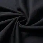 Tissu noir enroulé, texture douce et élégante, idéal pour la couture et la décoration intérieure.