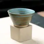 Coupe en céramique avec motifs géométriques, posée sur un socle en béton, idéale pour la décoration scientifique ou pour une collection d'objets décoratifs.