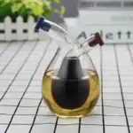 Vase de laboratoire en verre contenant un liquide noir, avec deux tubes en verre inclinés, utilisé pour des expériences scientifiques ou décoratives.