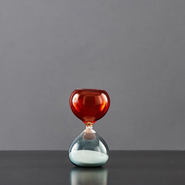 Balancier de sablier en verre rouge et transparent avec sable blanc.