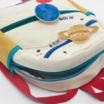 Sac à dos d'école blanc avec décor scientifique, featuring des patchs en peluche d'atomes et d'éléments chimiques, idéal pour les enfants passionnés de sciences.