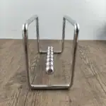 Pendulette Newton en métal brillant, illustrant la célèbre expérience de physique avec des sphères suspendues, sur une surface en bois clair.