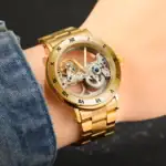 Montre squelette en or massif avec mécanisme visible, bracelet en acier doré, design élégant et sophistiqué. Parfaite pour les amateurs de montres mécaniques et de style luxueux.