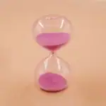 Sablier en verre transparent contenant du sable rose, symbole de temps et de patience, idéal pour la décoration scientifique ou éducative.