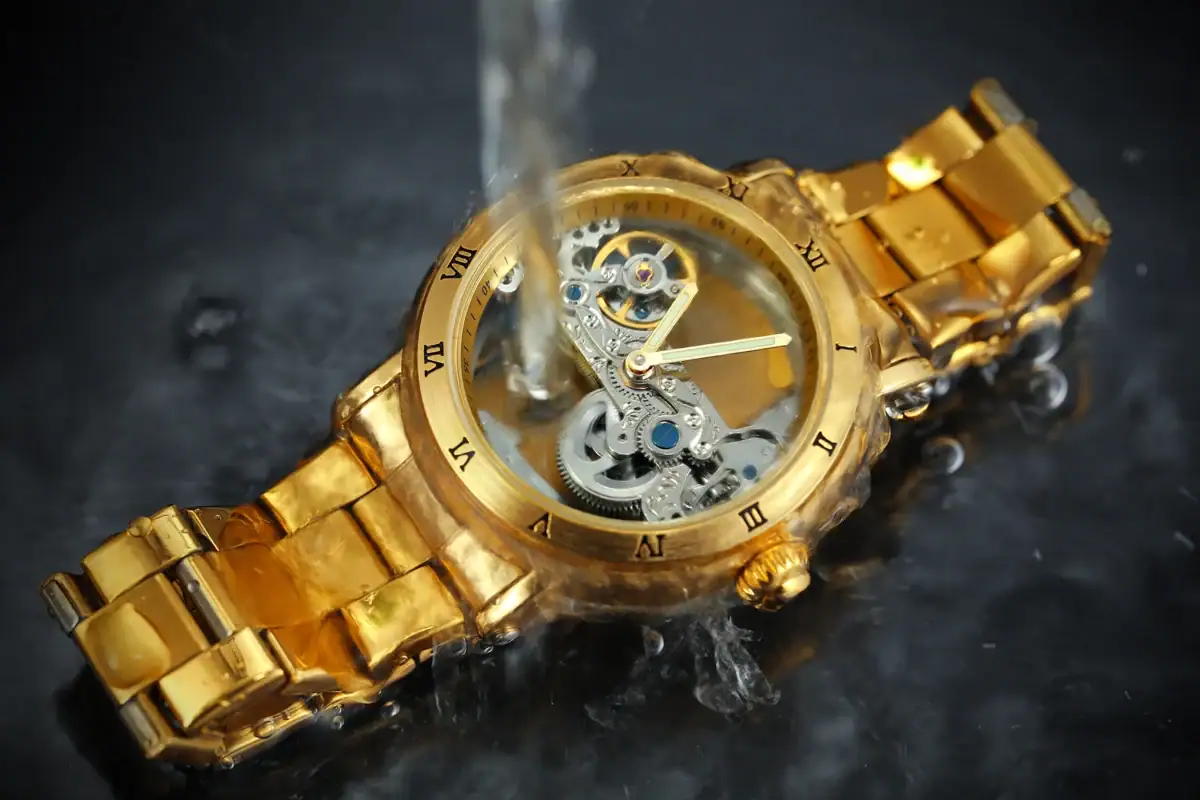 Montre mécanique dorée avec mouvement visible, immergée dans l'eau, mettant en valeur son design sophistiqué et ses détails techniques. Parfaite pour une décoration scientifique élégante.