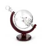 Boussole en verre représentant un globe terrestre avec un bateau miniature à l'intérieur, posée sur un support en bois. Idéal pour la décoration scientifique ou comme objet de collection.