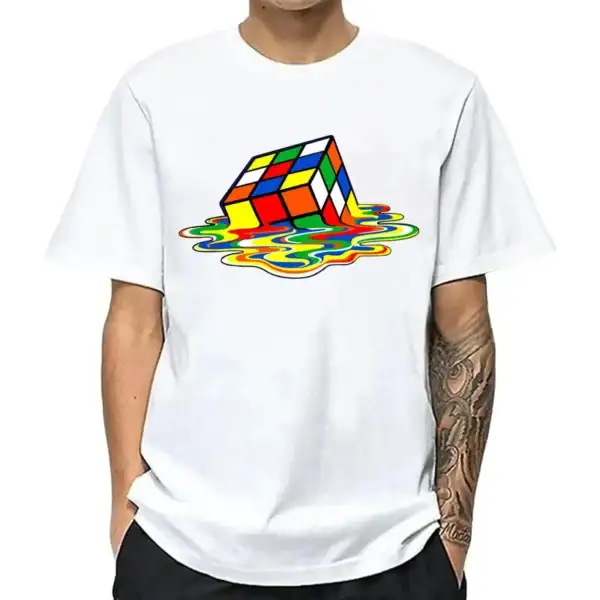 T-shirt blanc avec un design de cube Rubik coloré en train de fondre dans une flaque de peinture multicolore, style graphique moderne et ludique.