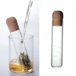 Pipette de laboratoire transformée en infuseur à thé, contenant du thé vert en infusion. Parfait pour une décoration scientifique originale ou une expérience de dégustation innovante.