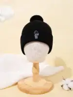 Bonnet en laine noir avec logo scientifique, orné d’un pompon, présenté sur un mannequin en bois, idéal pour accessoires de mode et décoration scientifique.