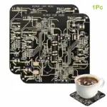Puce de circuit imprimé noire avec circuits dorés, utilisée comme décoration ou objet scientifique, accompagnée d'une tasse de café sur un sous-verre en circuit imprimé.