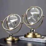 Horloge décorative en forme de sablier avec sphères en verre et structure en métal doré, inspirée du style astronomique, idéale pour la décoration intérieure.