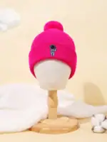 Bonnet rose en laine avec badge d'astronaute, accessoire chaud et tendance pour l'hiver, présenté sur un mannequin en bois dans un décor doux et minimaliste.