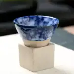Petite tasse en céramique avec motif marbré bleu et blanc, posée sur un support en béton, idéale pour la décoration scientifique ou pour une utilisation pratique.