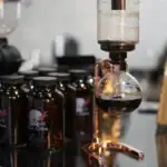 Dispositif de laboratoire avec bouteille de café noir, équipement scientifique pour expériences ou décoration thématique scientifique.