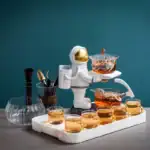 Décoration de thé originale avec un astronaute en céramique servant du thé chaud, entouré de tasses et accessoires de cuisine, sur fond bleu.