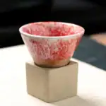 Petit pot en céramique rouge et blanc posé sur une base en béton, idéal pour la décoration scientifique ou botanique.