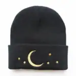 Bonnet en laine noir avec broderie de lune et étoiles dorées, parfait pour un style cosy et mystérieux.