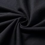 Ăchantillon de tissu noir enroulĂ©, montrant sa texture douce et fluide, idĂ©al pour la dĂ©coration ou la couture.