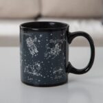 Mug en céramique noir avec illustrations des constellations du zodiaque : Gémeaux, Sagittaire, Lion, Bélier, et plus, avec noms en français.