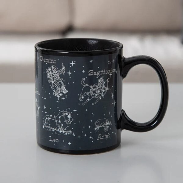Mug en céramique noir avec illustrations des constellations du zodiaque : Gémeaux, Sagittaire, Lion, Bélier, et plus, avec noms en français.