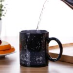 Tasse en céramique noire avec illustrations de constellations du zodiaque, Leo et Aries, sous un ciel étoilé, idéale pour les amateurs d'astronomie et de décoration scientifique.