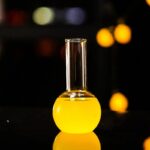 Vase de laboratoire en verre contenant un liquide jaune vif, utilisé pour des expériences scientifiques ou comme décoration d'inspiration scientifique.