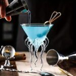 Vase en verre transparent avec support en forme de tentacules, idéal pour décoration scientifique ou moderne.