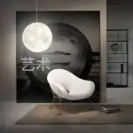 Lampe murale en forme de lune suspendue au-dessus d'un fauteuil moderne blanc dans un intérieur contemporain, avec étagÚre en arriÚre-plan.