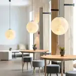 Suspension lumineuse en forme de lune, décoration intérieure moderne avec trois lampes suspendues rondes, ambiance chaleureuse et design épuré dans un espace contemporain.