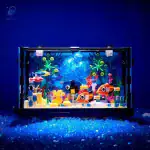 Vitrine d'aquarium scientifique avec décorations colorées, poissons en plastique et éléments marins, illuminée par une lumière bleue pour un effet captivant et éducatif.