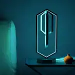 Clé LED moderne en forme de clé, éclairée d'une lumière bleue, posée sur une table avec une petite vase et un livre, décoratif et innovant pour un intérieur scientifique ou technologique.